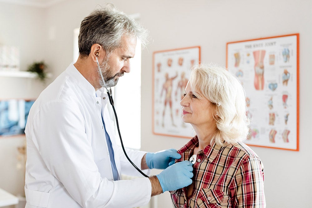Doctor examining heart of female patient