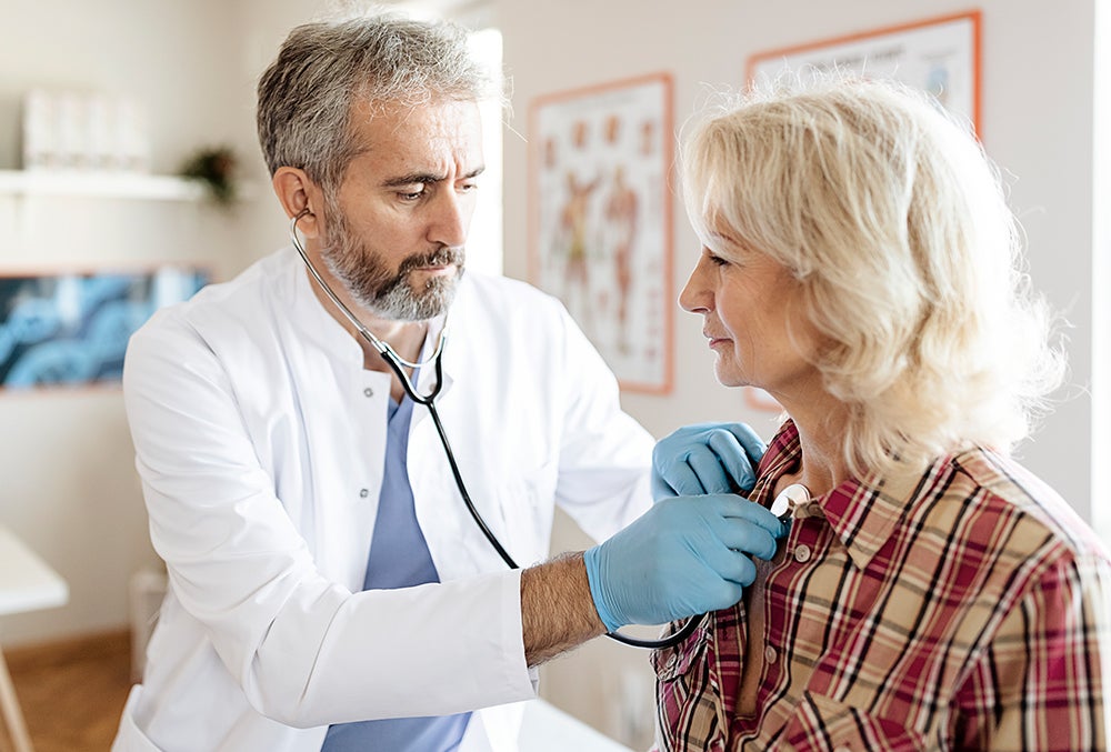 Doctor examining heart of female patient